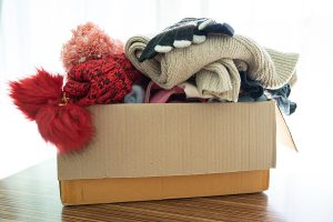 A box overflowing, ready to donate clothes to 