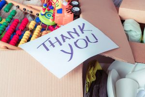 A box of toys for donation with a "thank you" sign on top